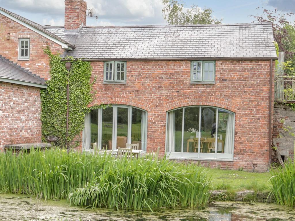 a brick house with large windows and plants at Glan Clwyd Isa - The Coach House in Denbigh