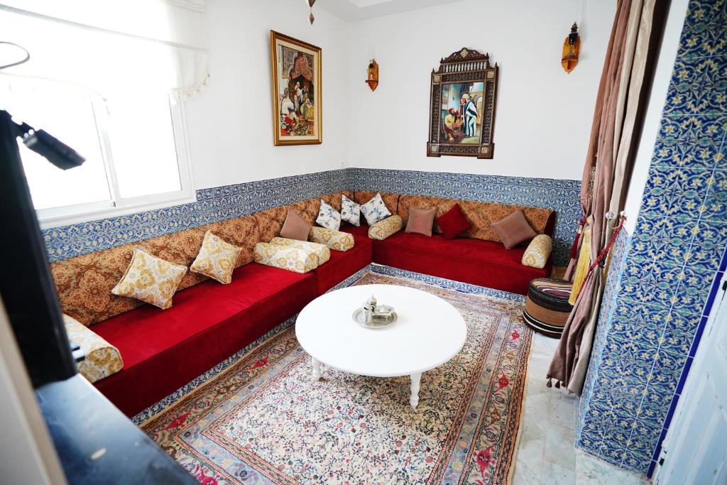 a living room with a red couch and a white table at DAR EL HAMRA in Mahdia