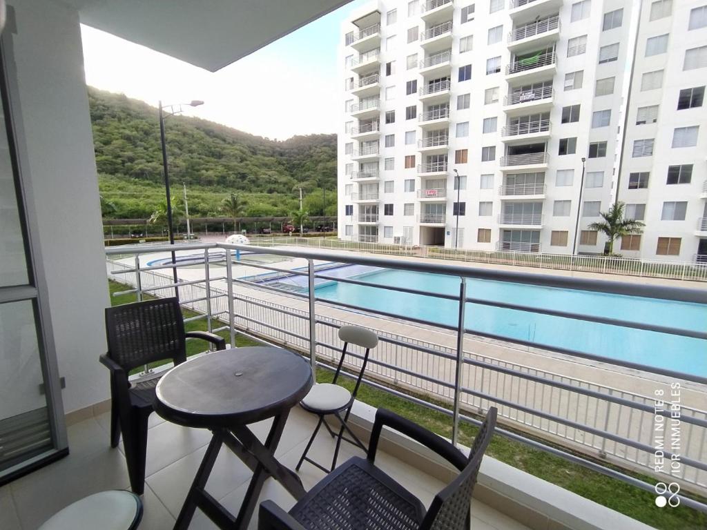 balcón con mesa, sillas y piscina en Apartamento Aqualina Orange Segundo Piso Vista a Piscina, en Girardot