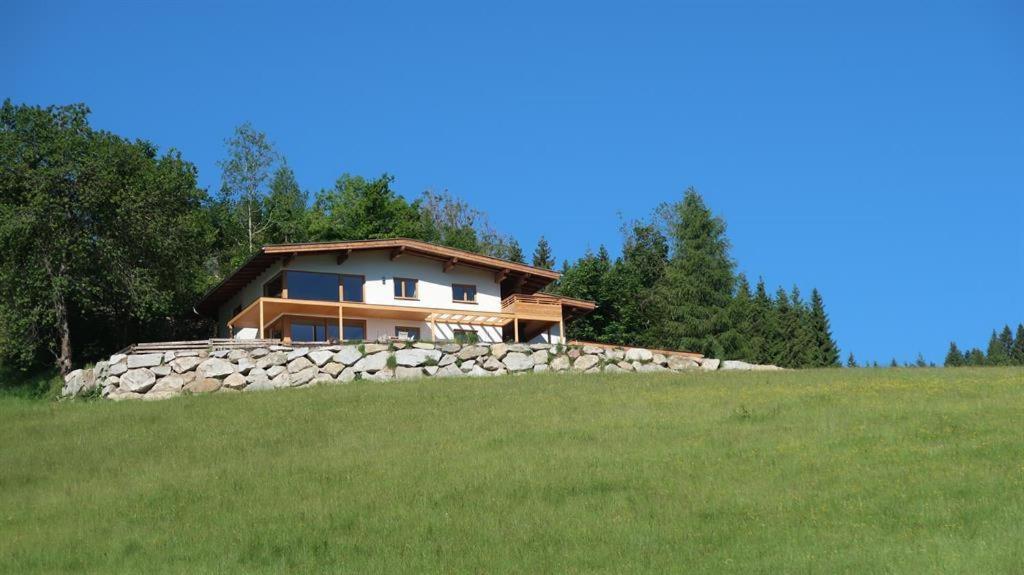 ein Haus auf einem Hügel mit einer Steinmauer in der Unterkunft Geelink's Berghütte in Itter