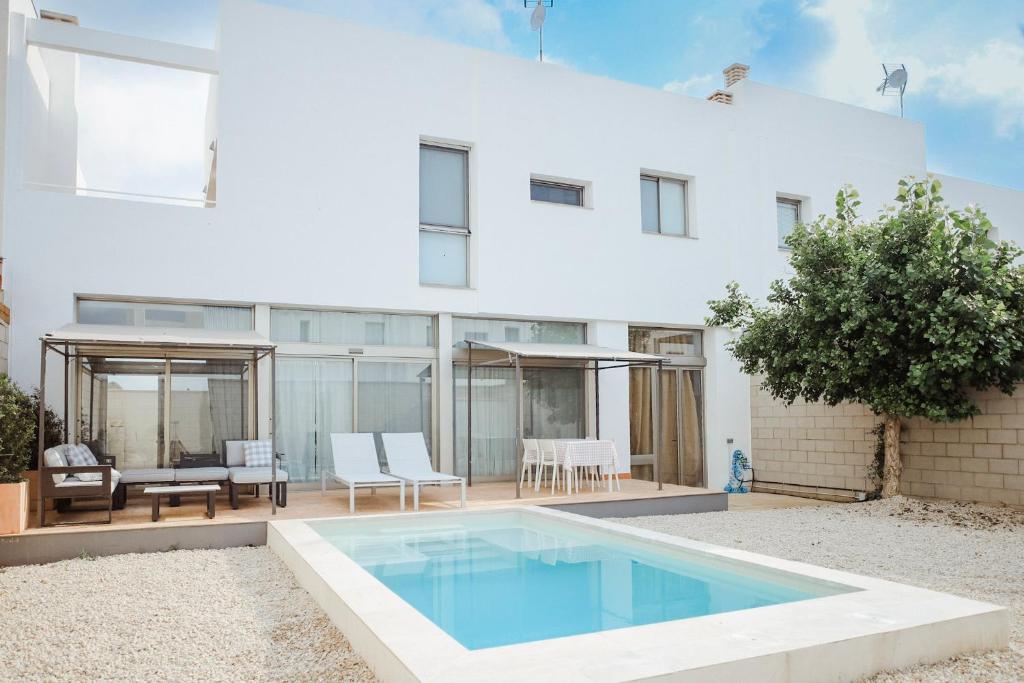 una casa blanca con piscina frente a ella en La Casita del Poble Nou del Delta, en El Poblenou del Delta