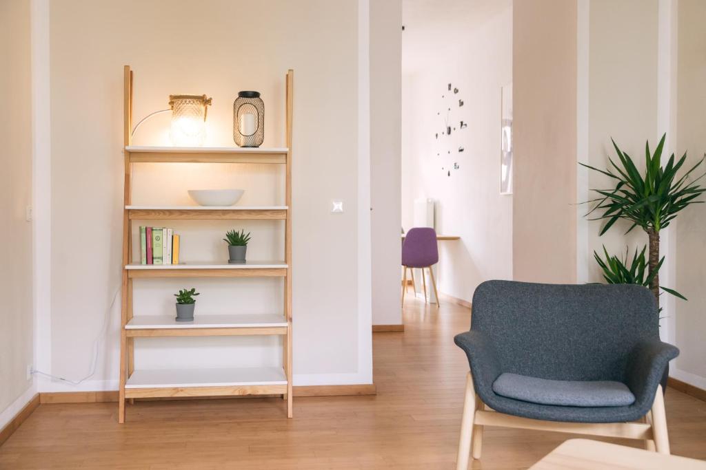 ライプツィヒにあるarena guest apartmentのリビングルーム(椅子、本棚付)