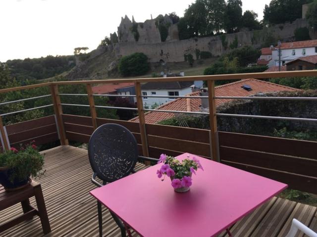 una mesa rosa con un jarrón de flores en el balcón en Les 3 pigeons en Bressuire