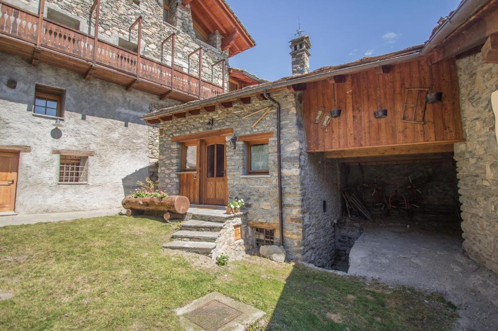 a stone house with a wooden door and a yard at La Grandze in Allein