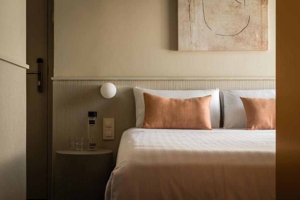 een slaapkamer met een bed met witte lakens en oranje kussens bij BYPILLOW The Bloom in Girona