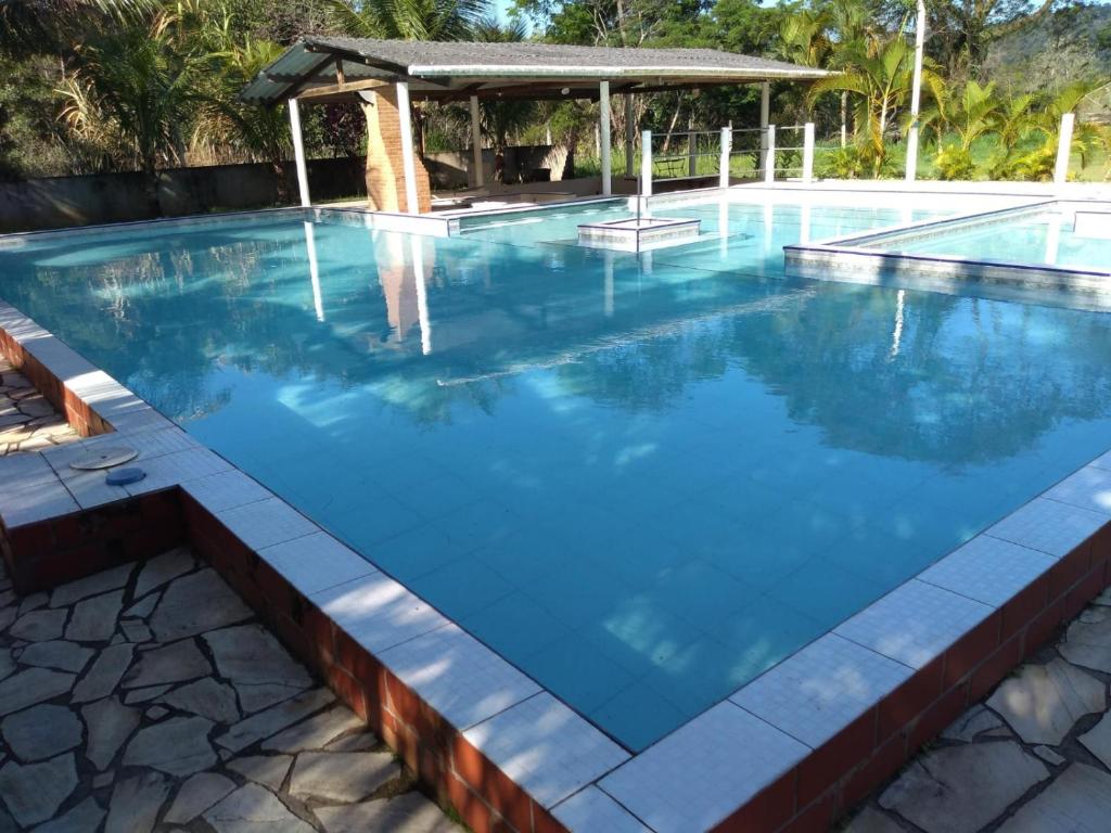 a swimming pool with blue water and a gazebo at Pousada do Veleiro Azul in Angra dos Reis