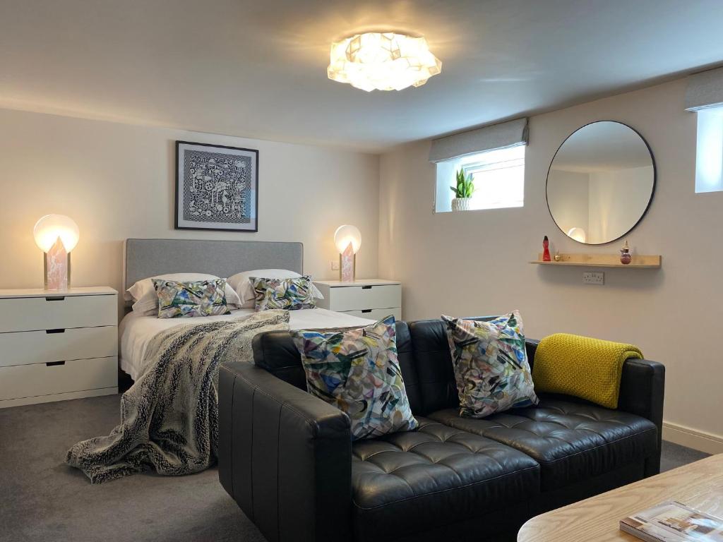 a bedroom with a bed and a couch and a mirror at Jays Bay Entire Luxury Apartment by the Beach Gt Yarmouth in Great Yarmouth