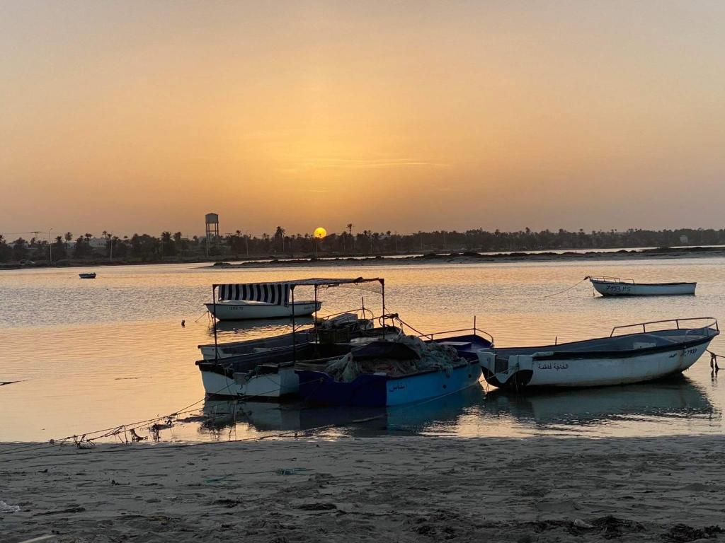 two boats sitting in the water at sunset at Villa DJERBA La Douce in Midoun