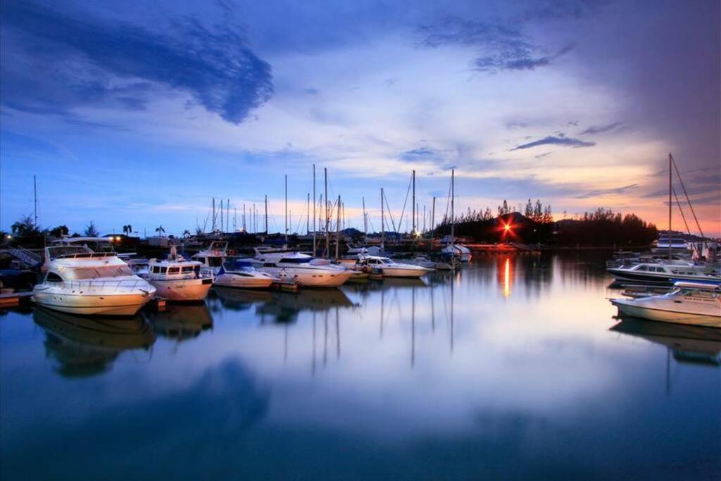 un grupo de barcos atracados en un puerto deportivo al anochecer en Marina Island Tiara Bay Villa, en Lumut