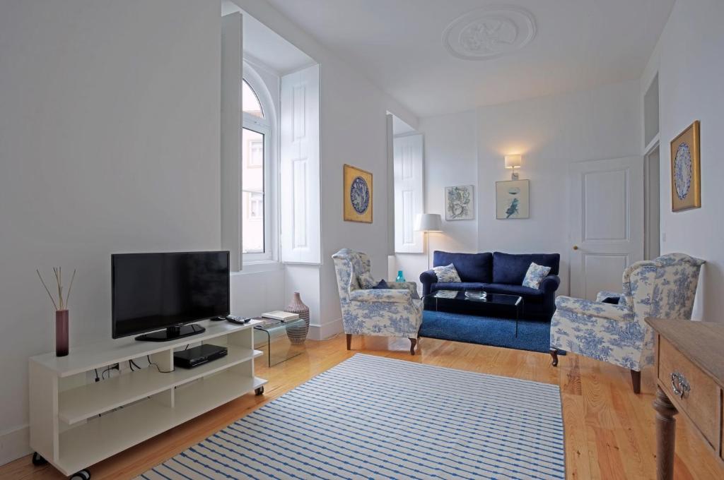 里斯本的住宿－Portas do Castelo Apartments，客厅配有电视和蓝色沙发。