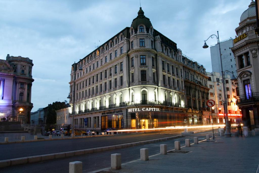 ブカレストにあるキャピトル ホテルの夜の街路大きな建物