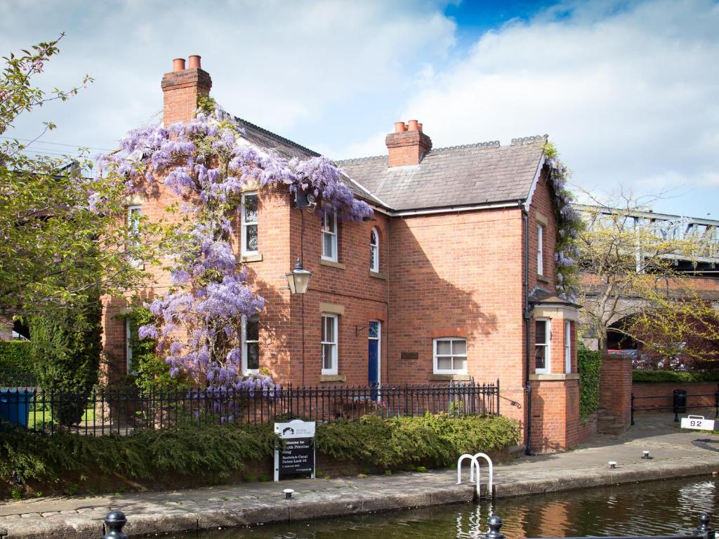 a house with purple flowers on the side of it at Lock Keepers Cottage - Detached House in the city in Manchester