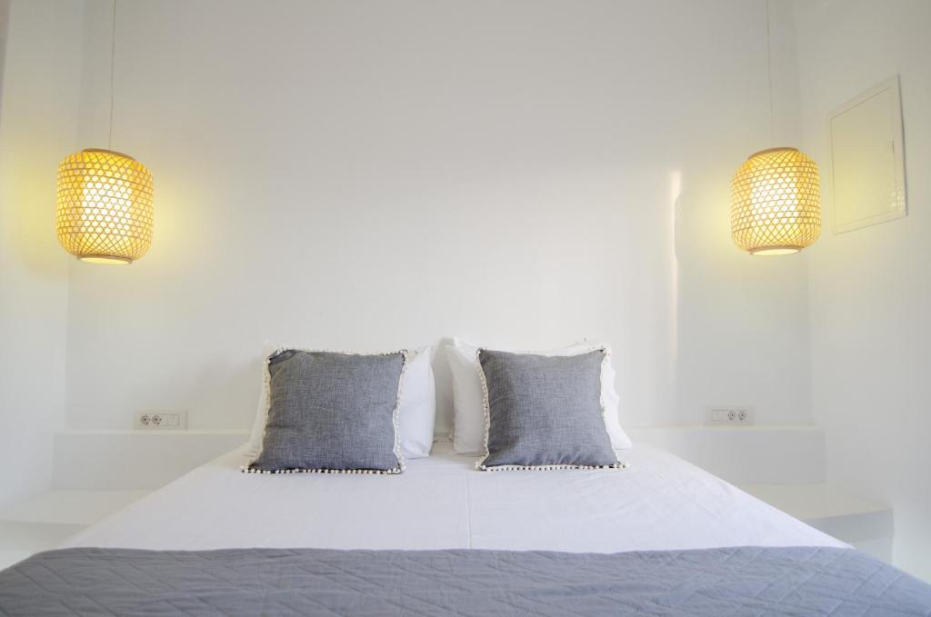 a bedroom with a bed with blue pillows and two lights at Maria's View Delux in Ios Chora
