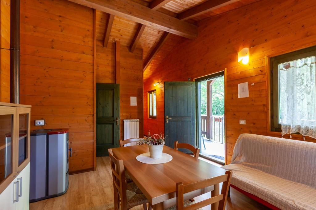 a dining room with a table and a couch at Villaggio Anemone - Chalet Anemone in Capanne di Sillano