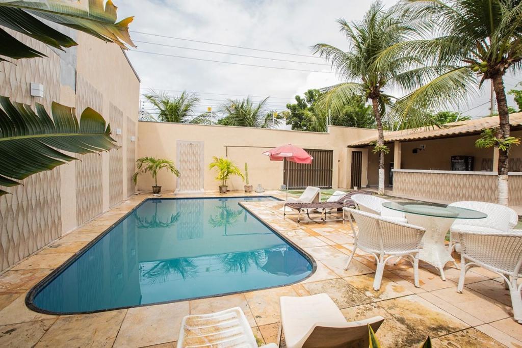 una piscina con sillas, una mesa y un patio en Porto das Dunas Casa Temporada Estilo e Conforto 2 en Aquiraz