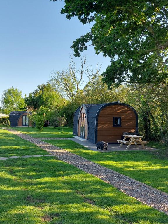 a cabin in a field with a dog in the grass at Oak Lodge Pods in Saint Lawrence