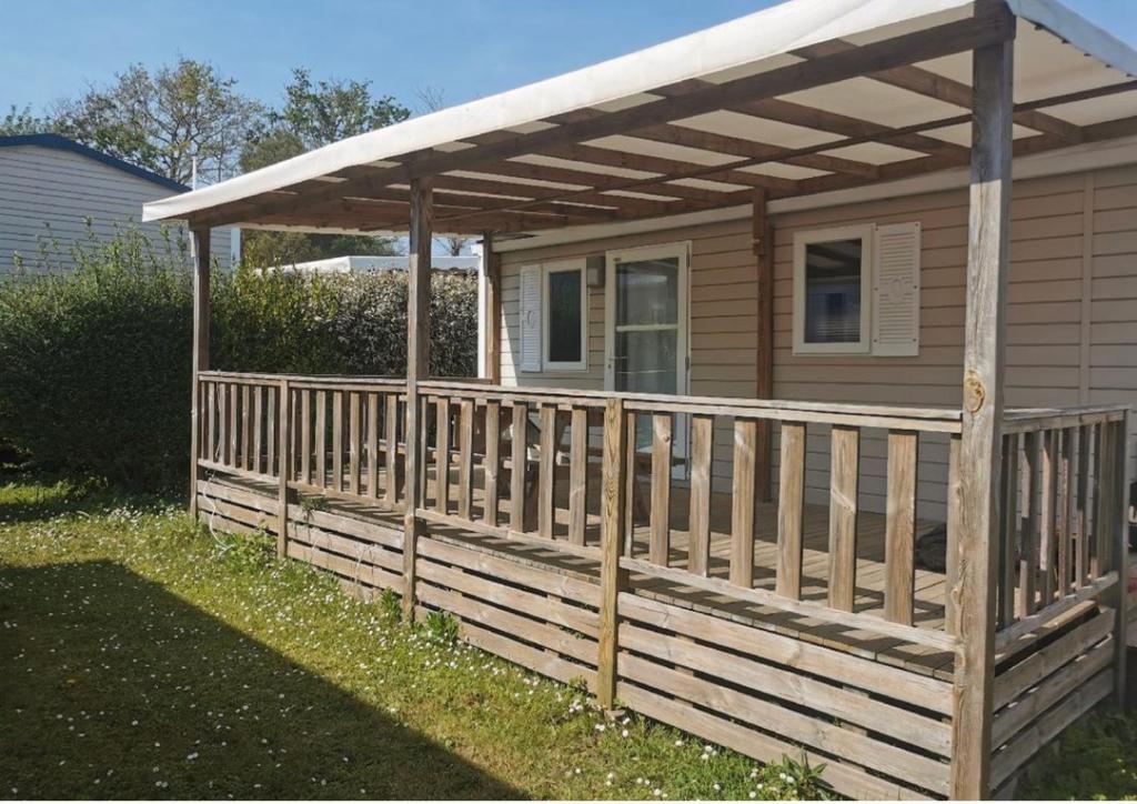 eine Holzterrasse mit einer Pergola auf einem Haus in der Unterkunft Mobil-Home 6 Places (3 chambres) tout équipé in Soulac-sur-Mer