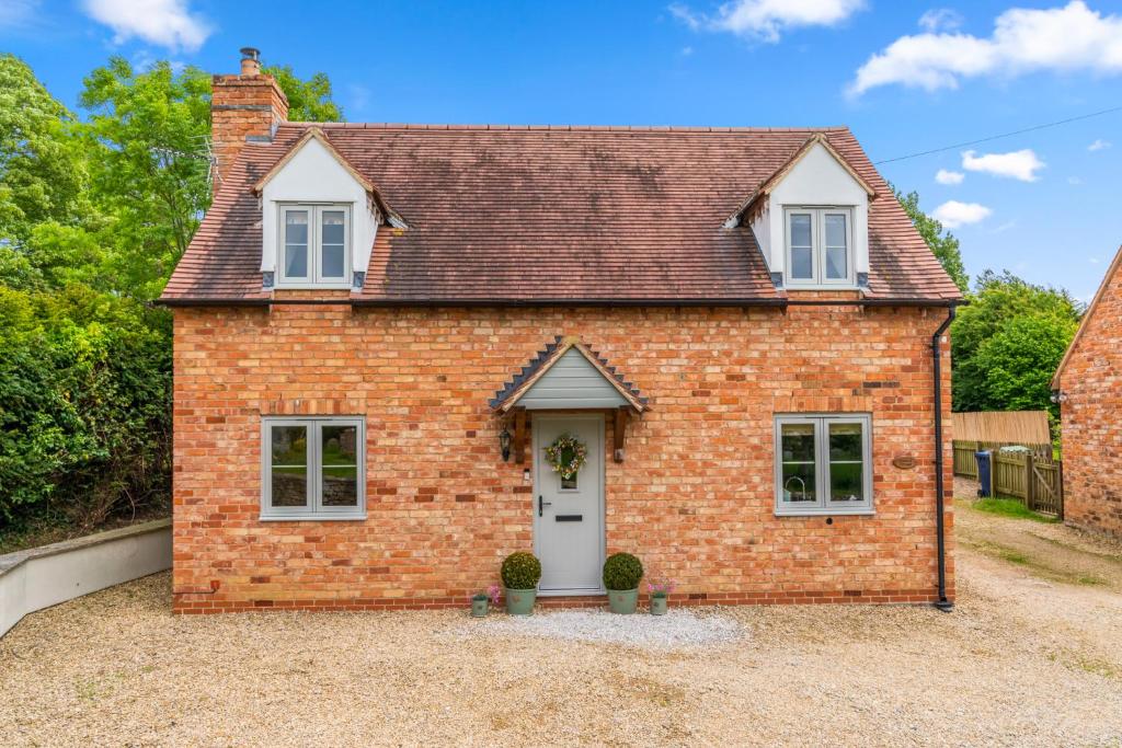 a red brick house with a white door at Orchard Cottage in Alderton
