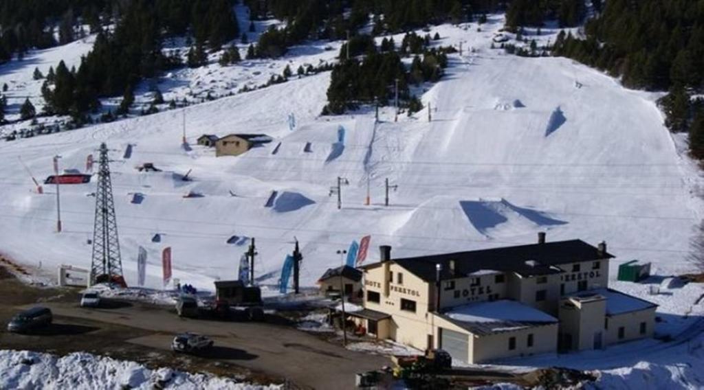 einen schneebedeckten Berg mit einer Skipiste mit einer Skihütte in der Unterkunft Hotel Peretol in Soldeu