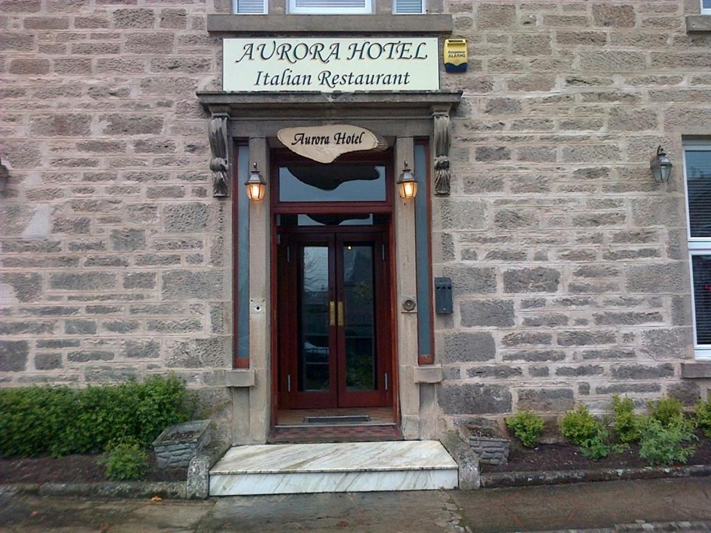 a building with a wooden door with a sign above it at Aurora Hotel & Italian Restaurant in Nairn