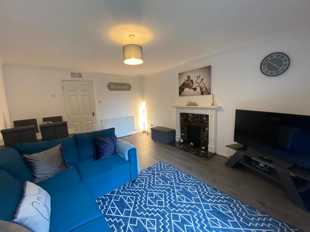 a living room with a blue couch and a fireplace at Marie’s 3 bedrooms Shakespeare house in Bedford