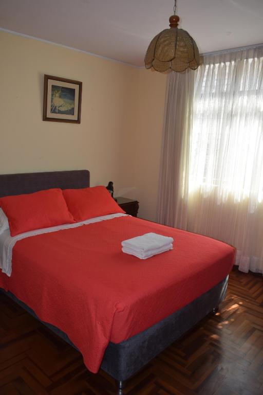 - une chambre avec un lit doté de draps rouges et une fenêtre dans l'établissement Hostal Donde Alberto, à Trujillo