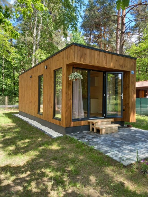 a small wooden cabin with a bench in a yard at Domek letniskowy Ostróda Arizona in Ostróda