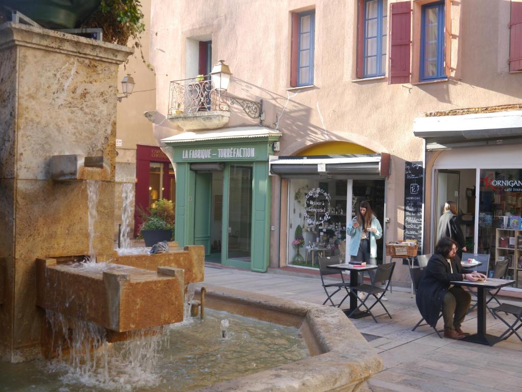 une fontaine au milieu d'une rue avec des bâtiments dans l'établissement Aux 4 FONTAINES, à Narbonne