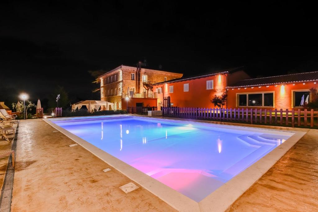 a large swimming pool at night with a house in the background at Relais Paradiso Resort & Spa in Gualdo Cattaneo