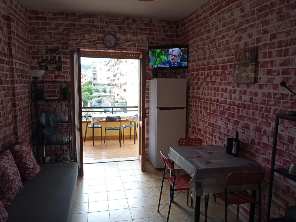 una cucina con tavolo e televisore su un muro di mattoni di Appartamento Via Pitagora a Scalea