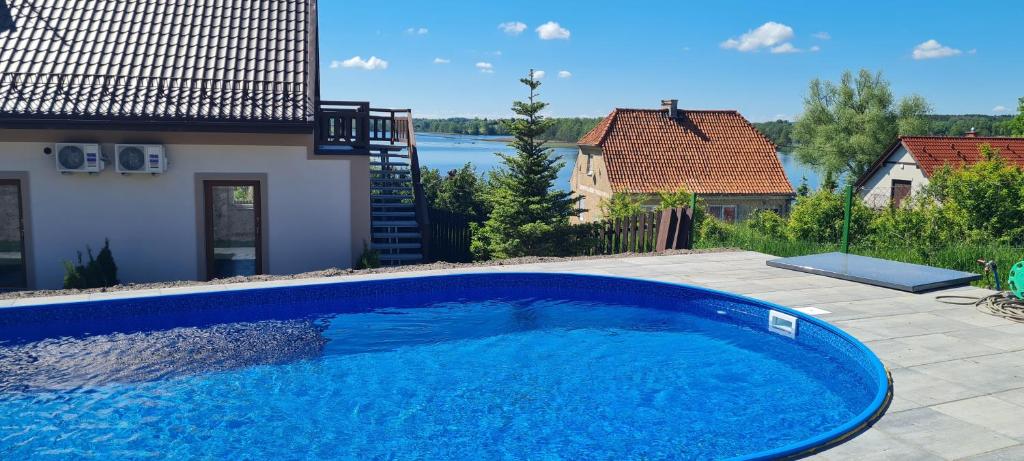 a large blue swimming pool in the backyard of a house at Apartament 4 osobowy z tarasem Zełwągi 15 in Mikołajki