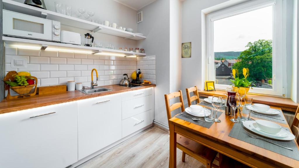 een keuken met een houten tafel met stoelen en een raam bij Apartament "Nad Jedlicą" in Kowary