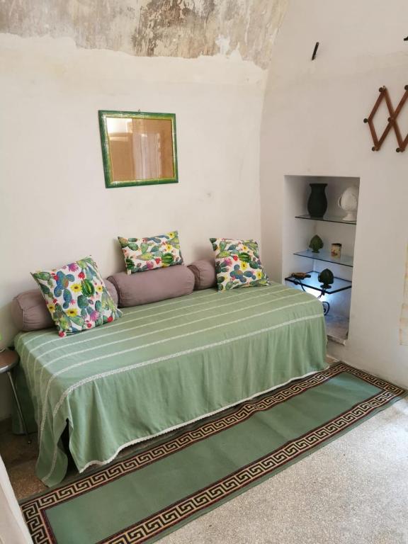 um quarto com uma cama verde com almofadas e um espelho em Santino Casa em Galatone