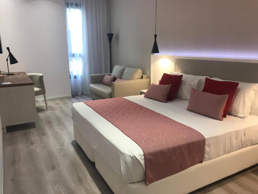 a bedroom with a large white bed with red pillows at Silken Rona Dalba in Salamanca