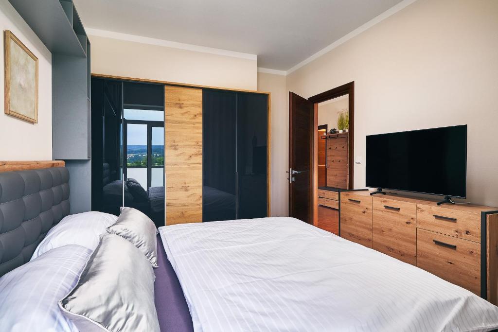 a bedroom with a bed and a flat screen tv at Apartman Residence Moser 1504 in Karlovy Vary