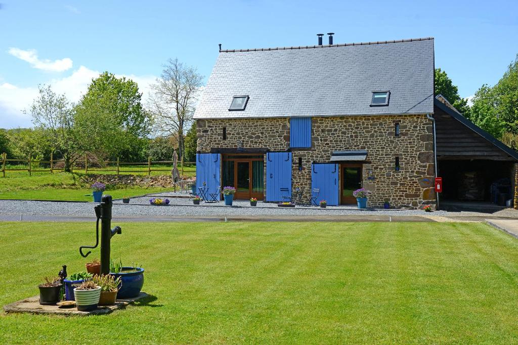 una casa in pietra con porte blu e un cortile di La Martinière a Saint-Aubin-Fosse-Louvain