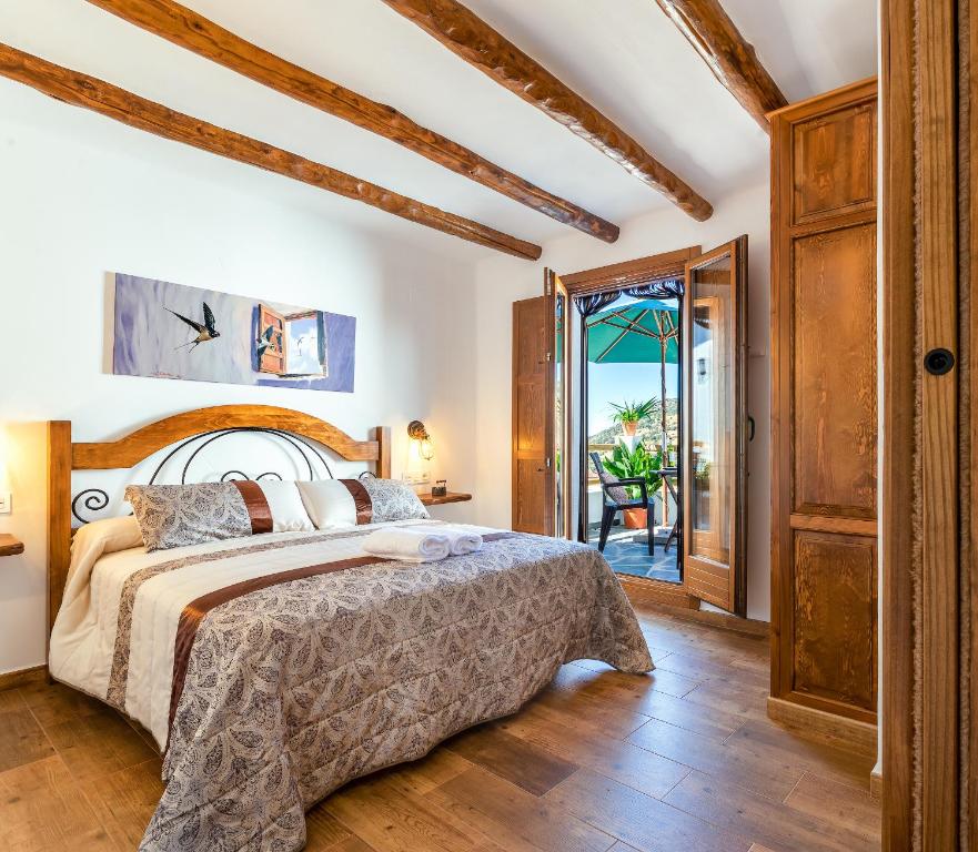 1 dormitorio con 1 cama y puerta que conduce a un patio en Apartamentos Entre Senderos, en Capileira