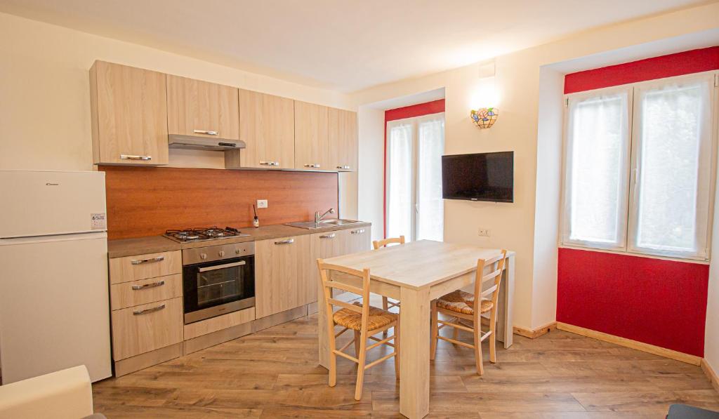 uma cozinha com uma mesa de madeira, uma mesa e cadeiras em La primula della Valle Soana em Ronco Canavese