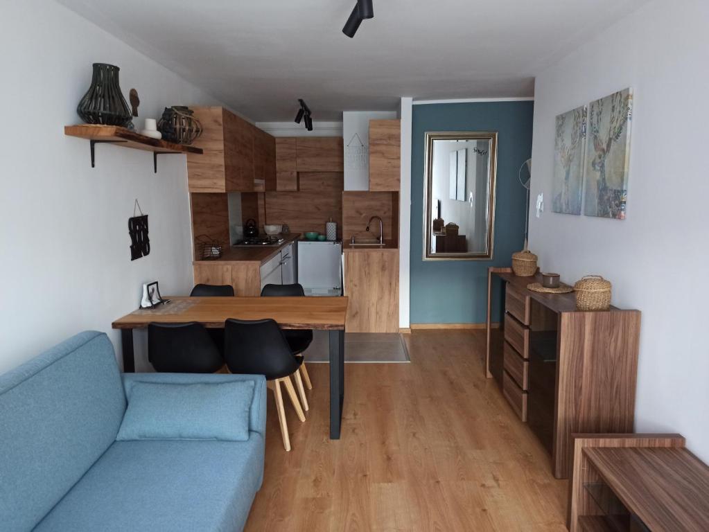 a living room with a blue couch and a table at Uroczy apartament nad morzem Gdańsk in Gdańsk