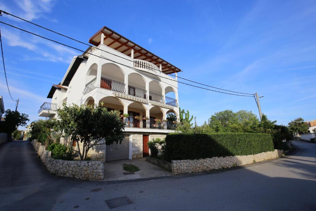 a white building with a balcony on a street at Apartmani Olga in Bibinje