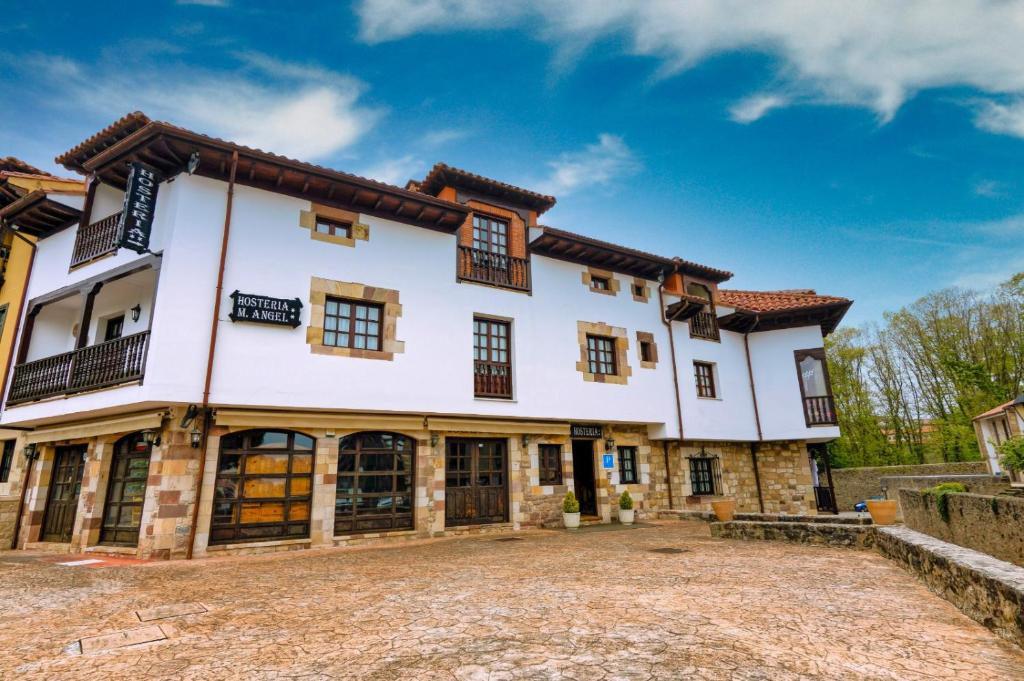 an exterior view of a large white house with a driveway at Hostería Miguel Angel in Santillana del Mar