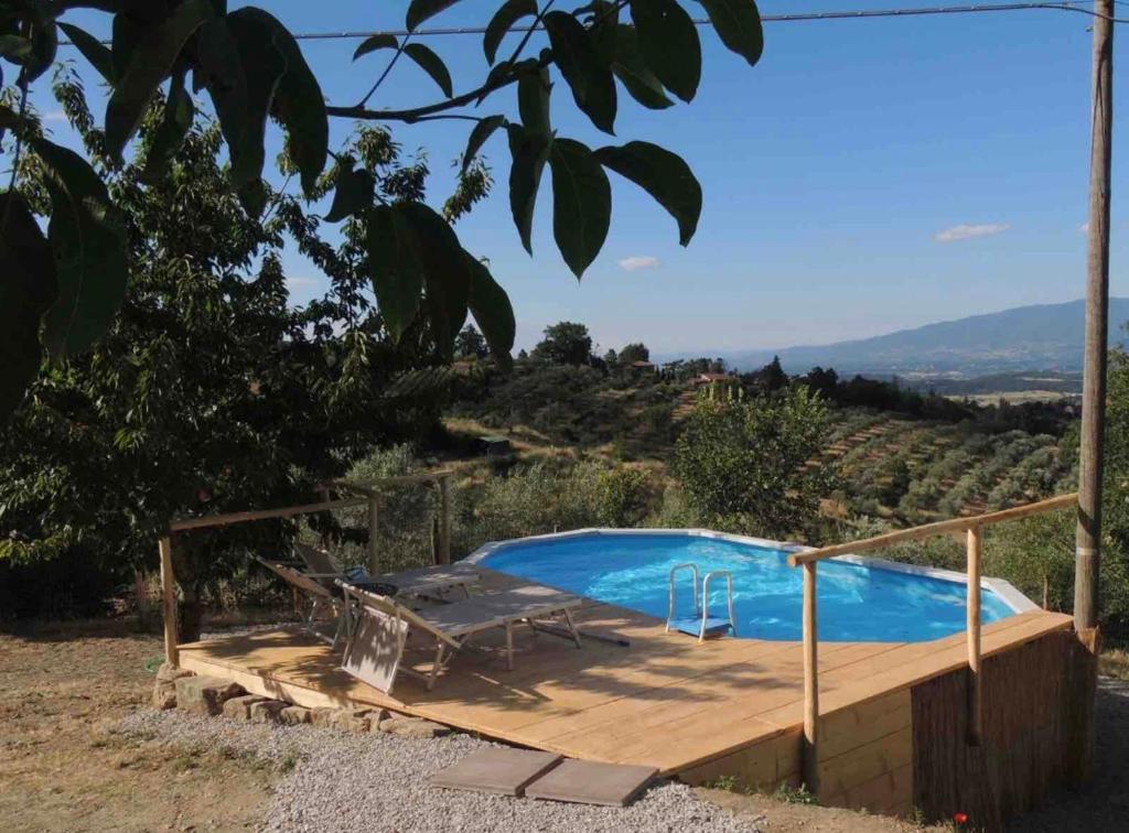 a swimming pool with a wooden deck next to a hill at al Poderuzzo in Castelnuovo deʼ Sabbioni