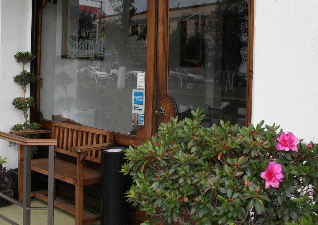 um banco sentado em frente a uma porta com flores em HB Express Hotel em Tlaxcala de Xicohténcatl