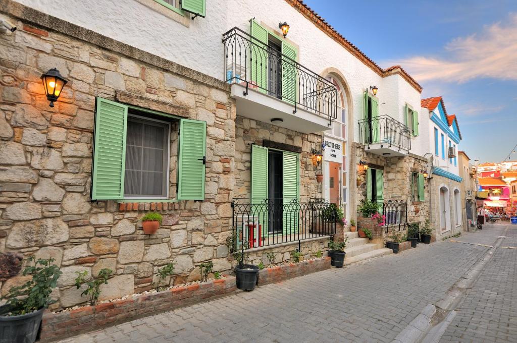 a stone building with green shutters on a street at Brothers Çeşme Boutique Hotel in Cesme