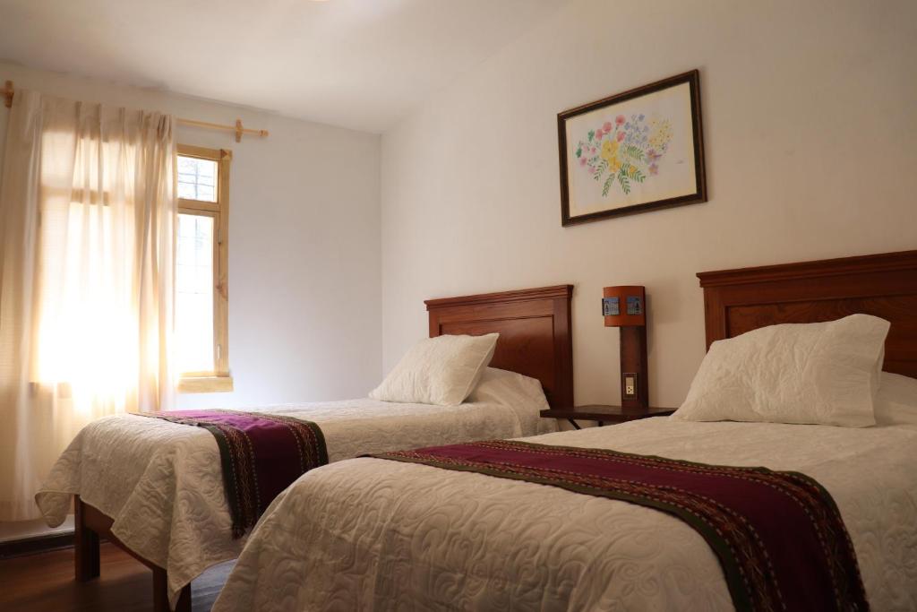 a hotel room with two beds and a window at Casa Gabriel in Cusco