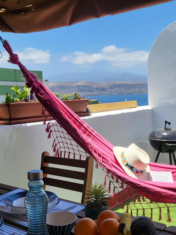 a hammock on a balcony with a view of the ocean at Apartamento calandria confital para 8 con terraza y BBQ próxima playa in Las Palmas de Gran Canaria