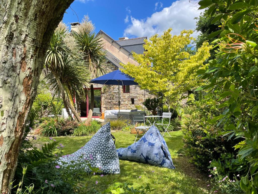 - un jardin avec 2 chaises et un parasol dans l'établissement La Corne de Cerf, Forêt de Brocéliande, à Paimpont