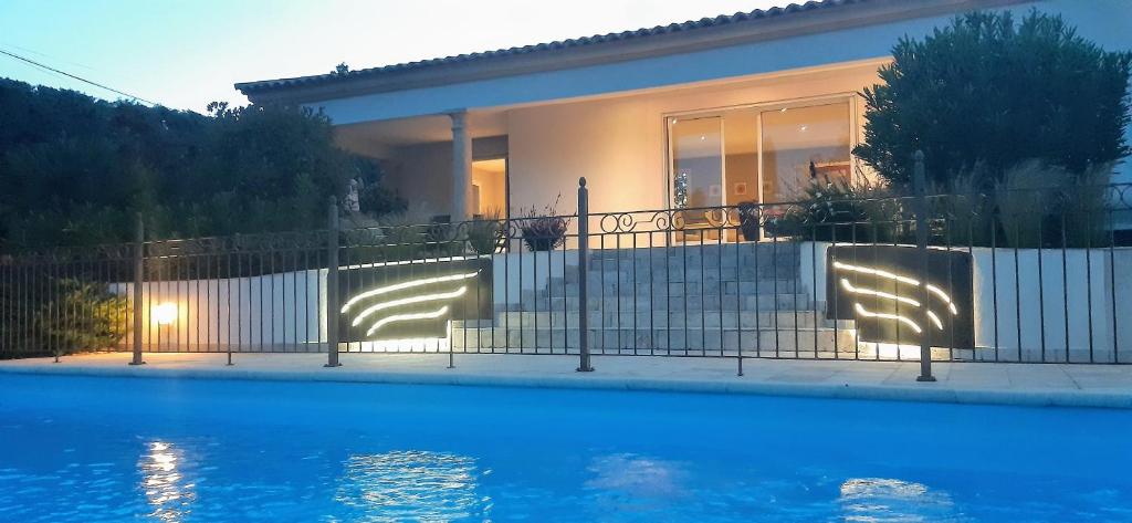 a house with a fence next to a swimming pool at Villa Jasmin Regusse in Régusse