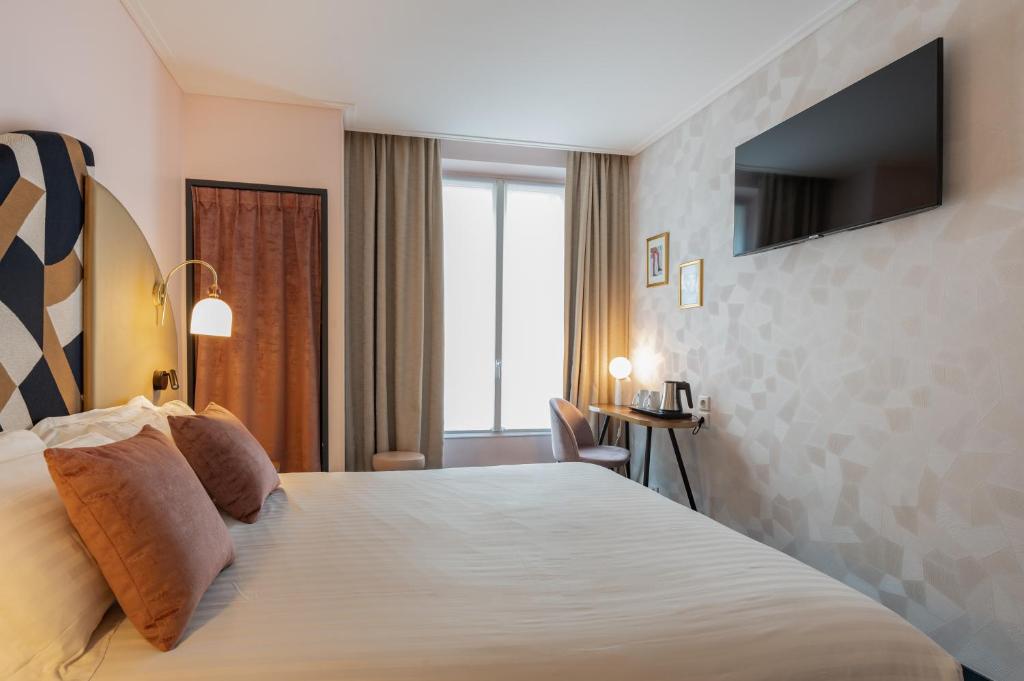 um quarto de hotel com uma cama grande e uma televisão em Royal Saint Germain em Paris