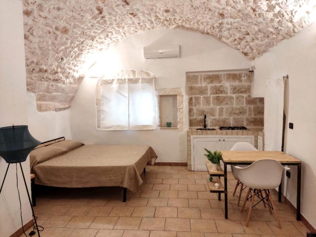 1 dormitorio con 2 camas, mesa y cocina en Minuetto 73, en Ostuni